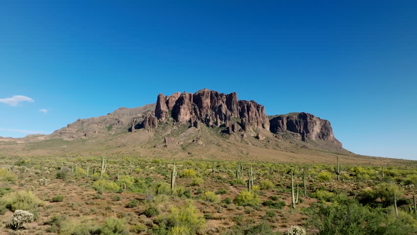Gradual establishing shot above saguaro cactus and sandy desert southwest landscape to Superstition Mountains Royalty-Free Stock Footage #3445103415