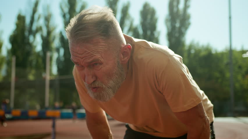 Pensioner breathing heavily after training physical activity elderly man dyspnea sporty athlete sportsman recreation stadium city outside vitality health hard working intense cardiovascular exhausted Royalty-Free Stock Footage #3445116191