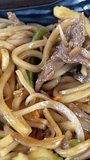 Freshly prepared beef lo mein is twirled on a fork.