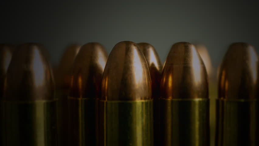 Gun Bullets Ammunition Close Up Ammo Zoom Out. Zoom out from a few gun bullets huddled together on a table. Tracking shot