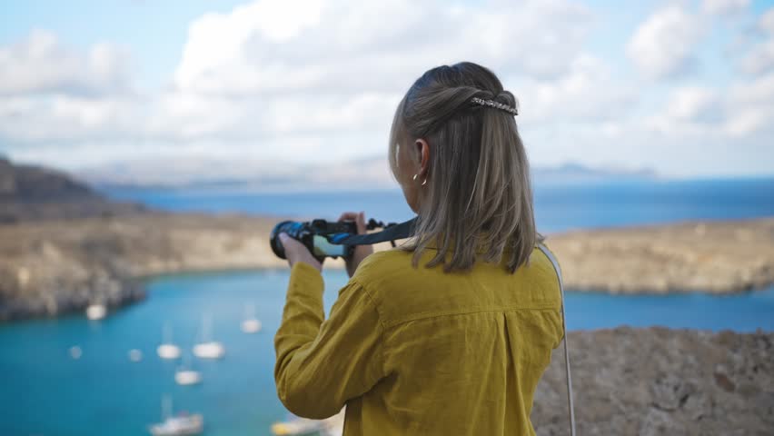 Woman photographer takes pictures of Lindos Bay.