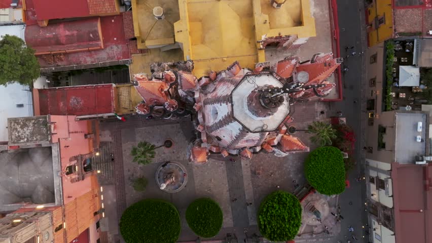 Rising drone shot showing tourist on square visiting mexican cathedral in San Miguel de Allende, Guanajuato. Aerial top down.
