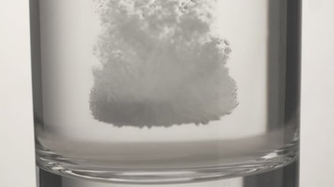 Effervescent aspirin tablet dropping to glass of water full HD video. Extreme close up slow motion fizzy pill falls and dissolves with bubbles. Medicine, health care pharmacy chemistry concept