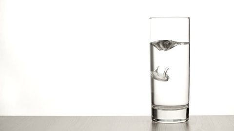 Effervescent aspirin tablet dropping to glass of water full HD video. Slow motion fizzy pill falls and dissolves with bubbles. Medicine, health care pharmacy chemistry concept