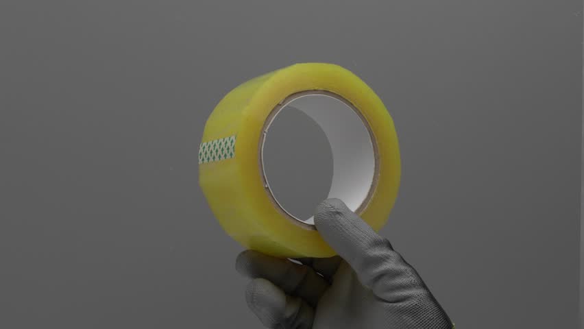 Transparent tape in hand on a gray background.