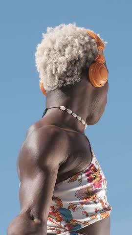 Transgender person dancing while listening to music with headphones outdoors. Technology concept.