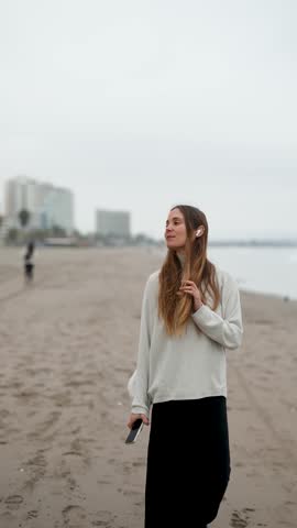 portrait beautiful caucasian woman walking relaxed on the beach listening to music	