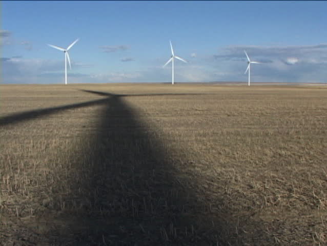 Wind turbine in open field with rotating shadow