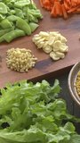 Ingredients for millet and vegetables stir fry. Millet, garlic, ginger, scalions, carrot, sugar snap peas. Table spin. Vertical video.
