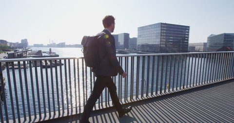 Young urban professional business man walking to work wearing backpack wearing backpack. Businessman in 30s in Copenhagen, Denmark, Scandinavia.