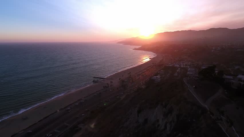 Aerial Beautiful View Of Wavy Sea By Mountains In City, Drone Flying Backwards During Sunset - Santa Monica, California