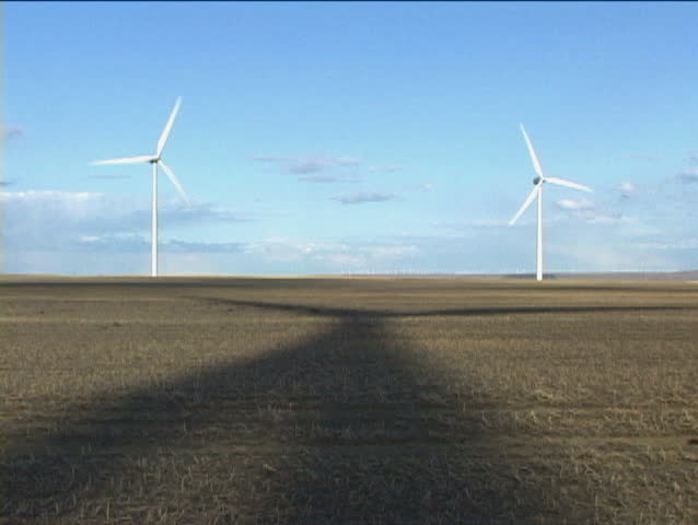 Wind turbine in open field with rotating shadow
