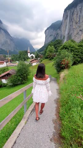a woman visiting Lauterbrunnen Valley with a gorgeous waterfall and Swiss Alps in the background, Berner Oberland, Switzerland, Europe in summer Royalty-Free Stock Footage #3445627331