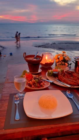 Asian woman having a romantic dinner on the beach in Thailand at sunset, Thai food at sunset on the beach of Koh Chang