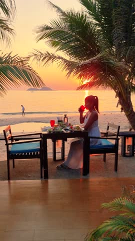 Asian woman having a romantic dinner on the beach in Thailand at sunset, Thai food at sunset on the beach of Koh Chang