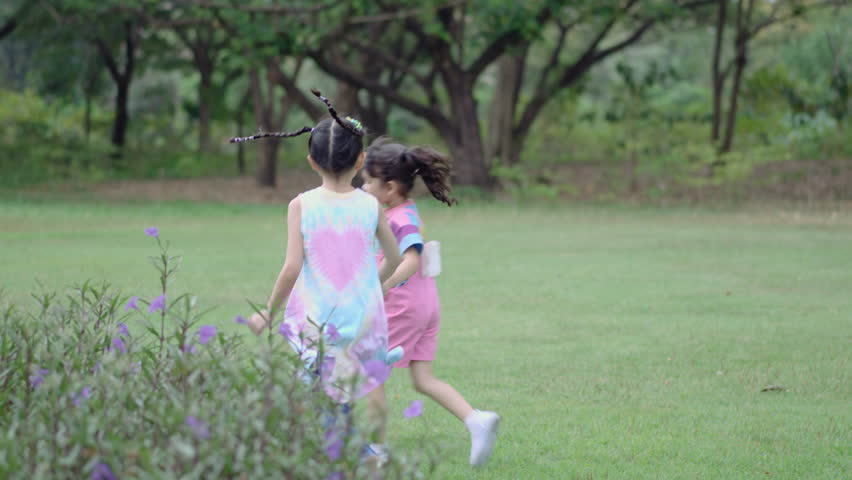 Little pretty girls having fun outdoor. Two cute girls are running around holding hands on green grass. Best friends.
