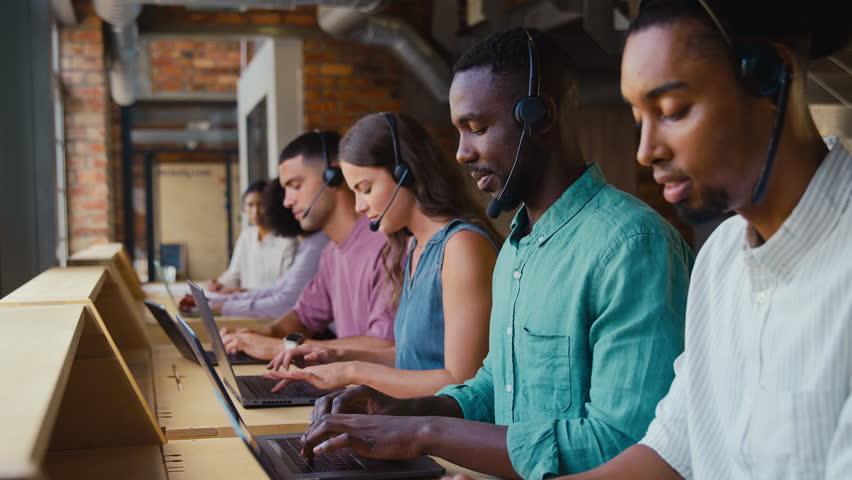 Multi-Cultural customer support or telesales team in modern open plan office wearing headsets and talking with customers - shot in slow motion - Powered by Shutterstock - Get 15% off with code: PIKWIZARD15