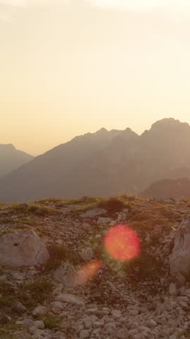 SLOW MOTION, LENS FLARE, CLOSE UP: Unrecognizable couple holding hands while hiking up to the mountaintop on a picturesque summer evening. Tourists in love enjoying a romantic hike and holding hands.