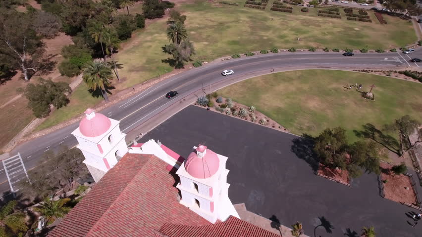 Aerial Panning Shot Of Mission Church By Cars Moving On Road During Sunny Day - Santa Barbara, California