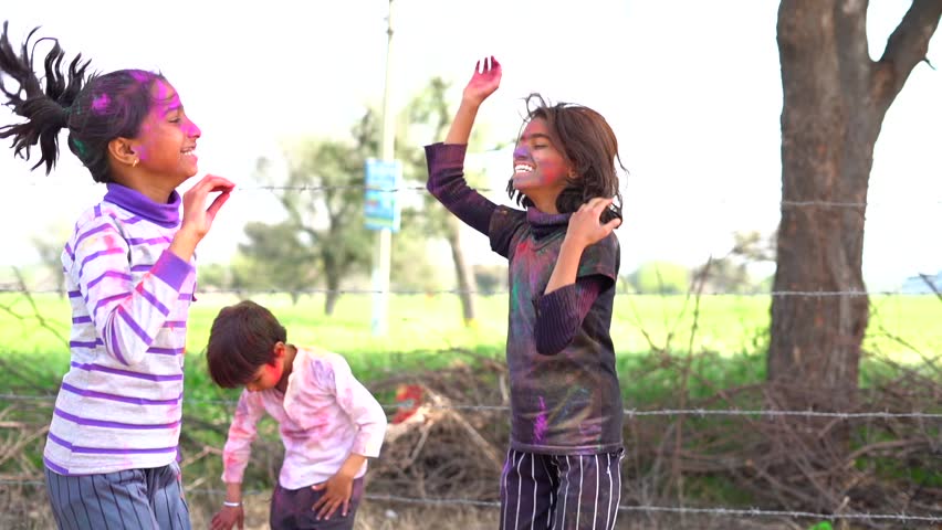 Bright and funny little girl playing with colors of Holi, festival of color