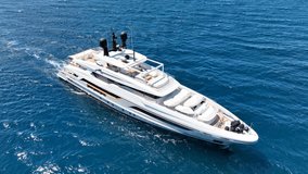 Aerial drone loop video of beautiful modern super yacht with wooden deck cruising in low speed in Aegean deep blue sea