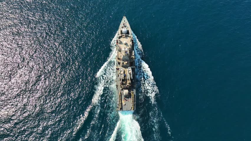 Aerial drone top down video of armed navy patrol frigate ship cruising deep blue sea