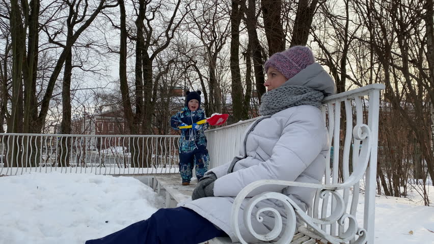 Playful child little boy throwing snow with shovel in winter park. Catherine Park, Pushkin, St. Petersburg.