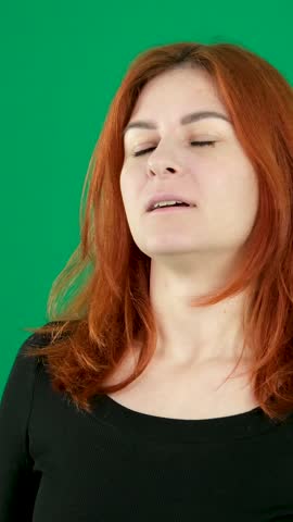 calm yourself slowly exhale and inhale hold your breath close your eyes face of a young red-haired woman on a green background taking a deep breath relaxation relaxation find calm in yourself Royalty-Free Stock Footage #3446091815
