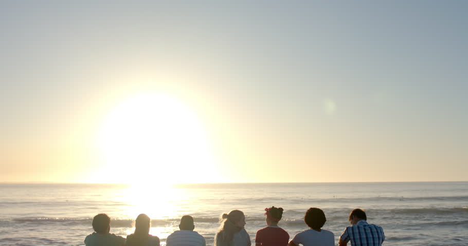 Diverse group of friends enjoy a serene beach sunset, with copy space. The outdoor setting creates a peaceful atmosphere for relaxation and bonding, slow motion. Royalty-Free Stock Footage #3446100913