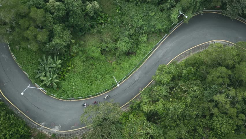 drone shot of professional cycling athletes training on s-shape rural road