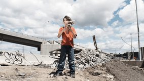 HD video of a young boy holding a plant surrounded by the urban jungle and destruction