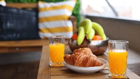 Breakfast from above. 4k video camera rotation with two croissants and orange juice in glasses on a wooden table. Breakfast video selective focus.