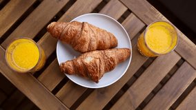 Breakfast from above. 4k video camera rotation with two croissants and orange juice in glasses on a wooden table. Breakfast video.