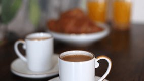 Selective focus 4k video with two cups of espresso coffee with croissants and orange juice in background. Home breakfast video.