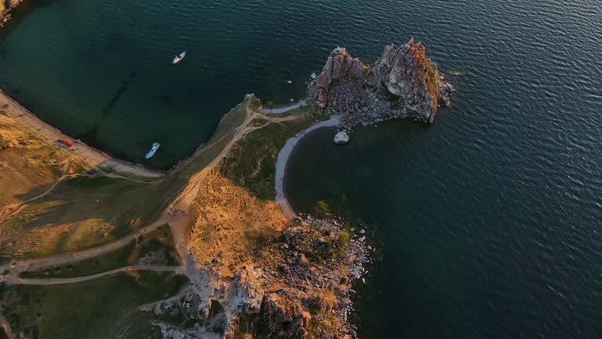 Aerial: Shamanka Rock (also Cape Burkhan, Shamanskiy Cape, Cave Cape) is a cape in the middle part of the western coast of Olkhon Island, on Lake Baikal. Summer view at sunset. Altai, Russia