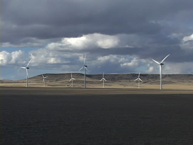 Row of wind turbines with cloudy sky and foreground shadow