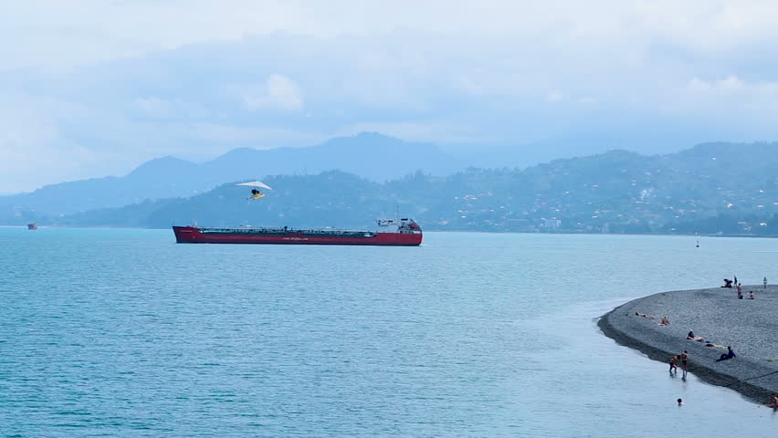 Seafront area with cargo ships and deltaplane in the sky in Batumi, resort city