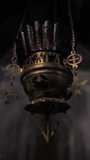 Vertical video: A gilded church lamp decorated with crosses and precious stones swinging on chains hanging in the church after a ritual or sacrament has been performed.