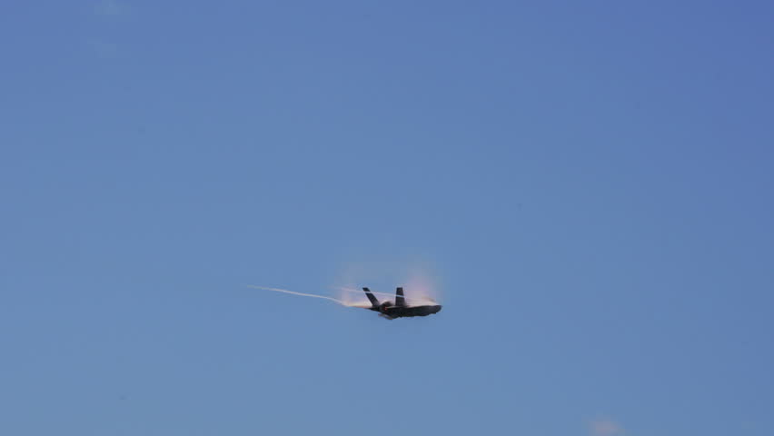 Tilt Up Shot Of Fighter Plane Leaving Contrail While Flying In Sky On Sunny Day - Huntington Beach, California