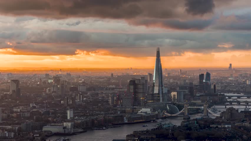 Panned sunset to night time lapse view of theskyline of London with golden sunlight and fast moving clouds