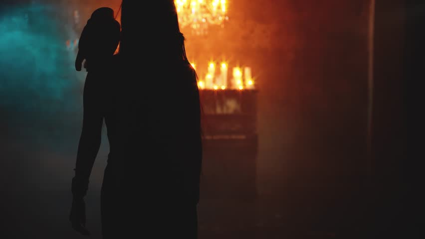 Art video shadow silhouette fantasy gothic woman with owl bird on shoulder walking in dark room, bright burning candles light old style. lady Elf back rear view long Blonde hair sexy fairy tale girl