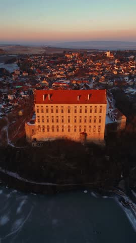 A castle on a rock at a beautiful sunset, a frozen lake under the castle