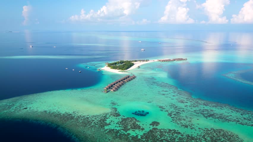 Aerial view of a beautiful paradise island in the Maldives with water bungalows over the turquoise ocean, coral reefs und fine, sandy beaches