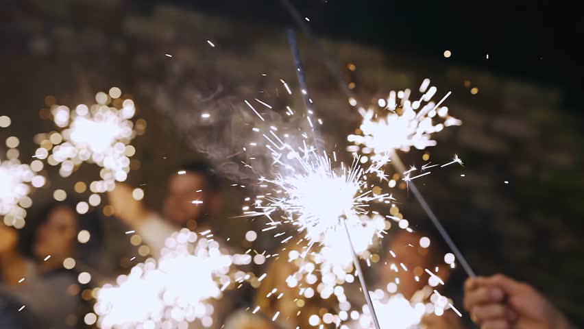 People at the festival hold burning sparklers in their hands. Beautiful sparks fly in different directions