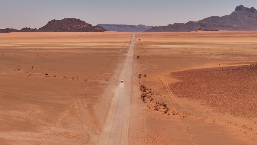 Aerial view of a 4x4 car driving on a gravel road in Namib desert in Sossusvlei National Park during a beautiful sunsets and vacations, Namibia, Africa Royalty-Free Stock Footage #3446468887