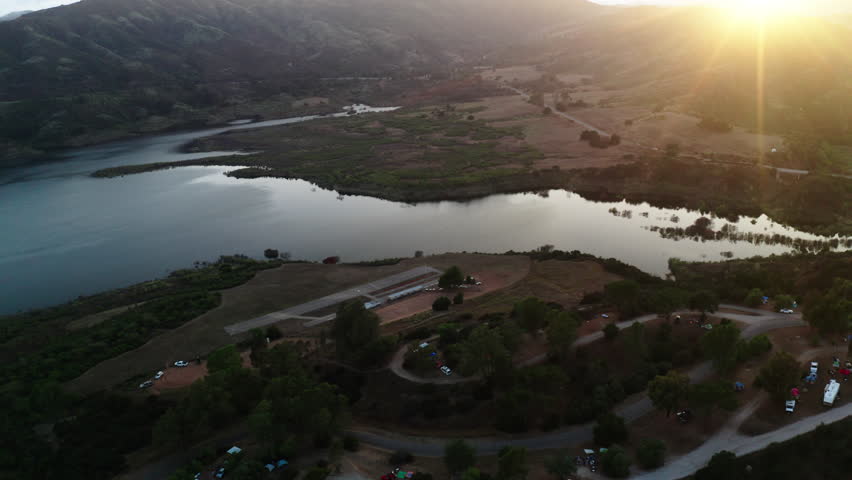 Aerial Forward Tilt Up Shot Of Lake Casitas Near Back Lit Mountains Against Sky - Ventura County, California