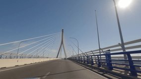 First person view, FPV, from dashcam of car driving across the Constitution of 1812 Bridge, La Pepa, in Cádiz, Andalusia, Spain, Europe. Road trip video in POV, with bright, sunny, clear blue sky
