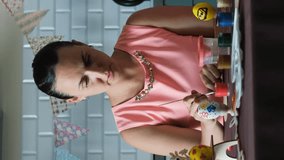 Vertical video. Young woman with daughter preparing for Easter holidays, paiting egg in the kitchen