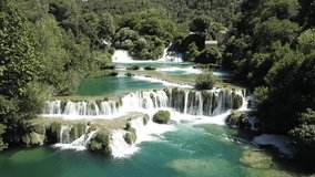 Aerial shot of a beautiful waterfall between trees on a sunny day, above Karka Falls, Croatia