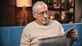 Portrait of old man with newspaper at home, elderly male person reading news and article, relax time. Grey-haired grandfather resting alone in evening in apartment, retirement and aging of people - Powered by Shutterstock - Get 15% off with code: PIKWIZARD15
